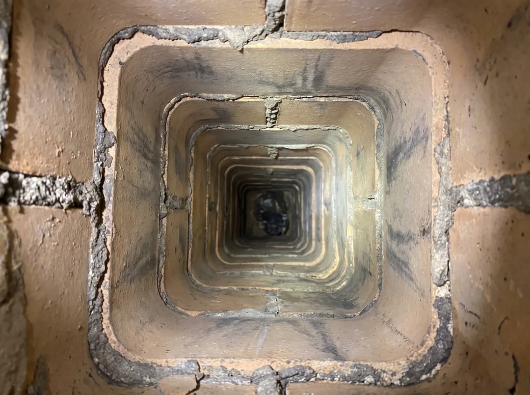 The same clay flue liner after sweeping, clean tile visible down the flue